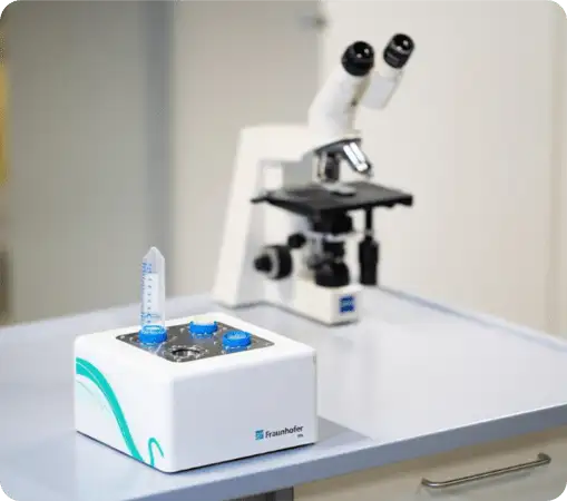 Automated lab device for sample preparation with a centrifuge tube, microscope in the background.